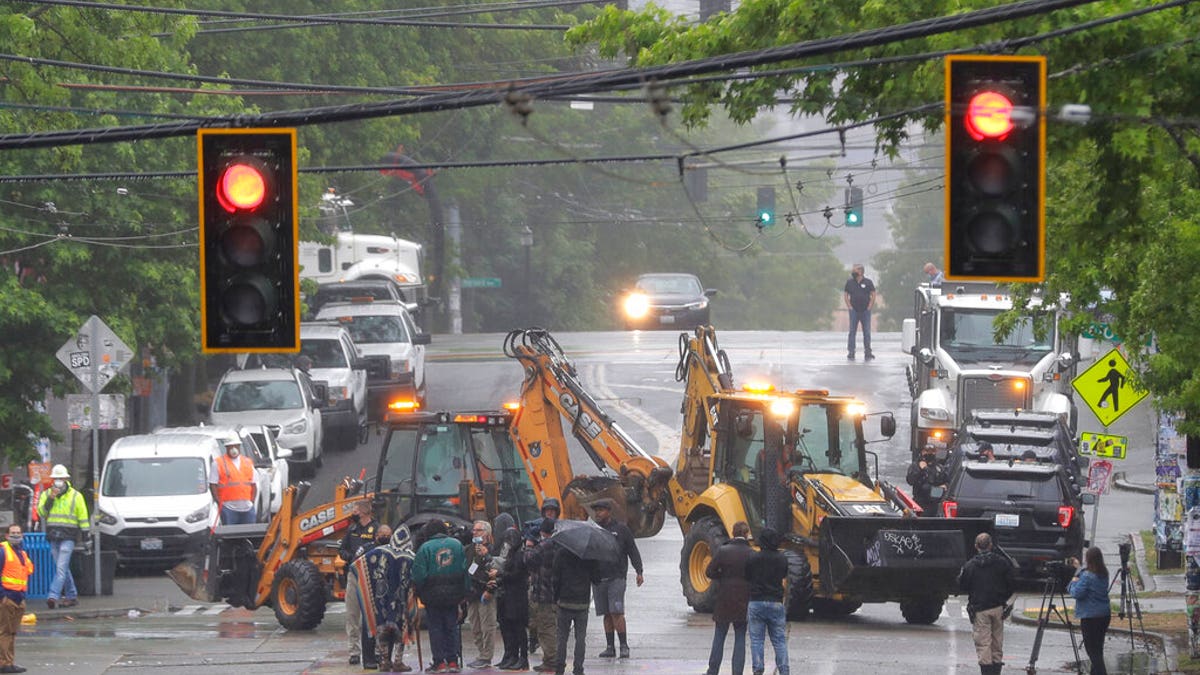 Seattle Department of Transportation workers remove barricades at the intersection of 10th Ave. and Pine St. on Tuesday at the CHOP zone in Seattle. Protesters quickly moved couches, trash cans and other materials in to replace the cleared barricades. (AP Photo/Ted S. Warren)