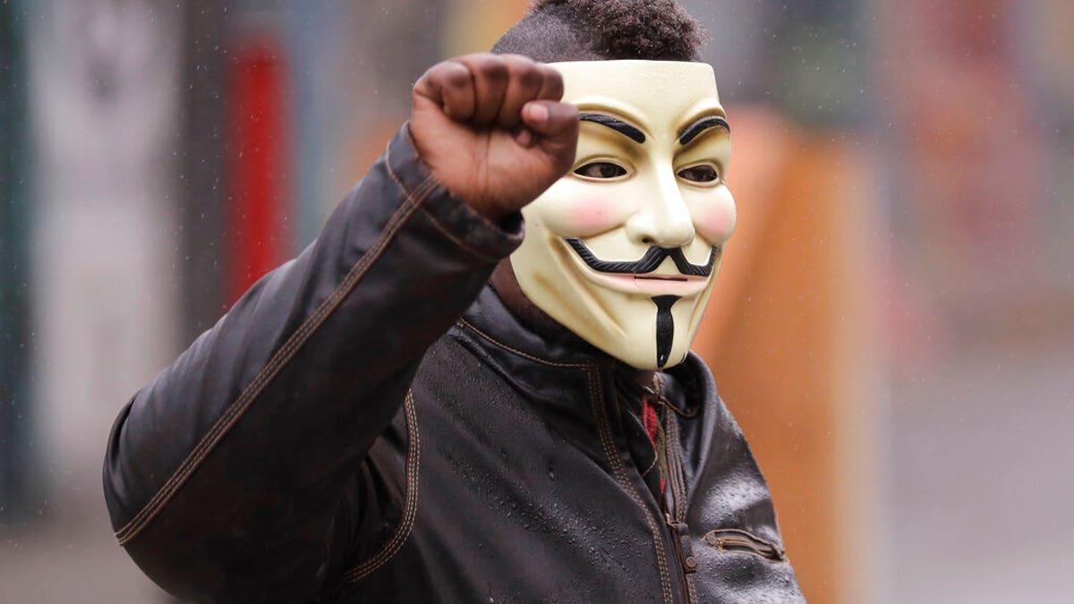 A protester raises his fist as he wears a Guy Fawkes mask near the Seattle Police Department East Precinct building, Tuesday, June 30, 2020 at the CHOP (Capitol Hill Occupied Protest) zone in Seattle.