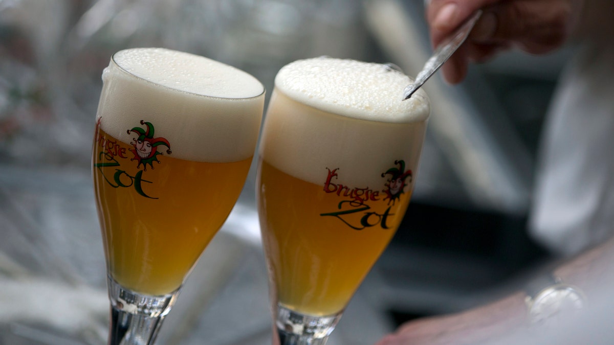 A worker scrapes the foam off of a glass of beer before serving in Bruges, Belgium. (AP)