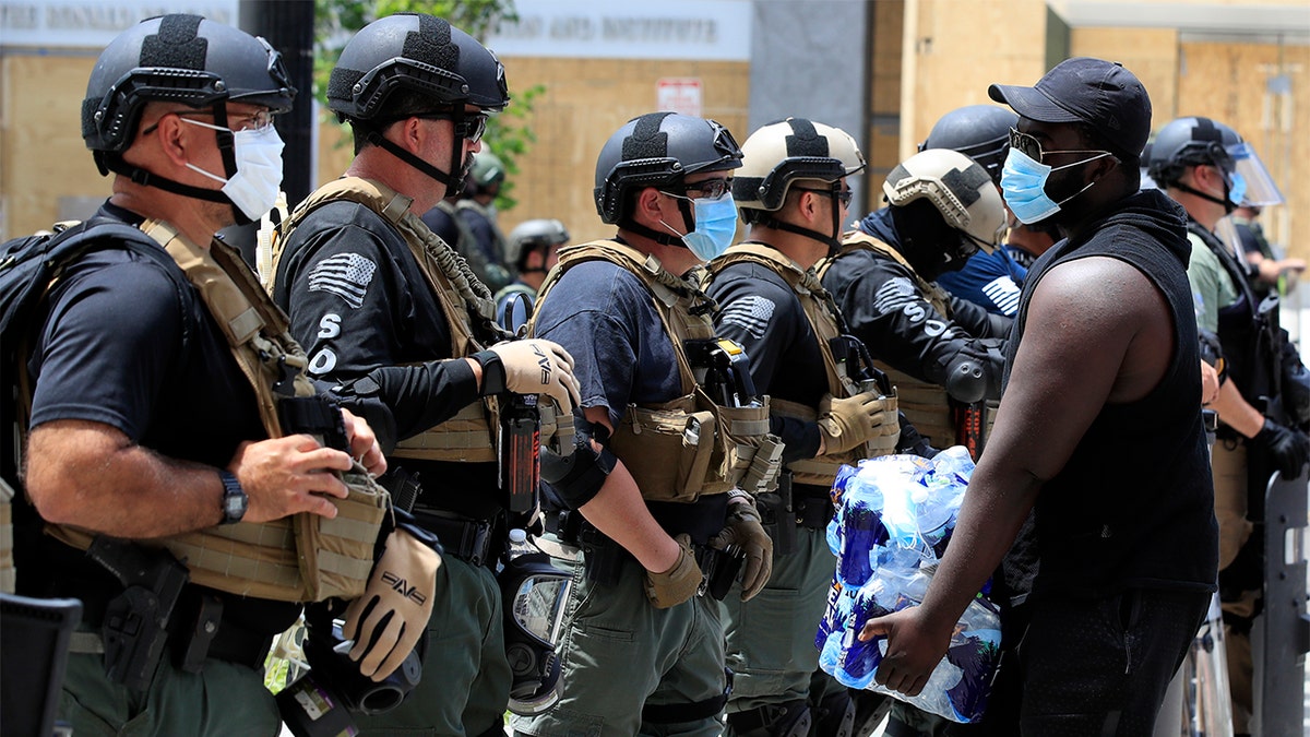 A demonstrator carrying water approaches as line of police as during a protest over the death of George Floyd, Wednesday, June 3, 2020, near the White House in Washington. Floyd died after being restrained by Minneapolis police officers. (AP Photo/Manuel Balce Ceneta)