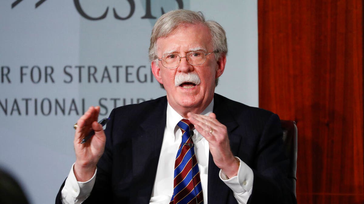 Trump national security adviser John Bolton speaks in a black suit with a blue striped tie