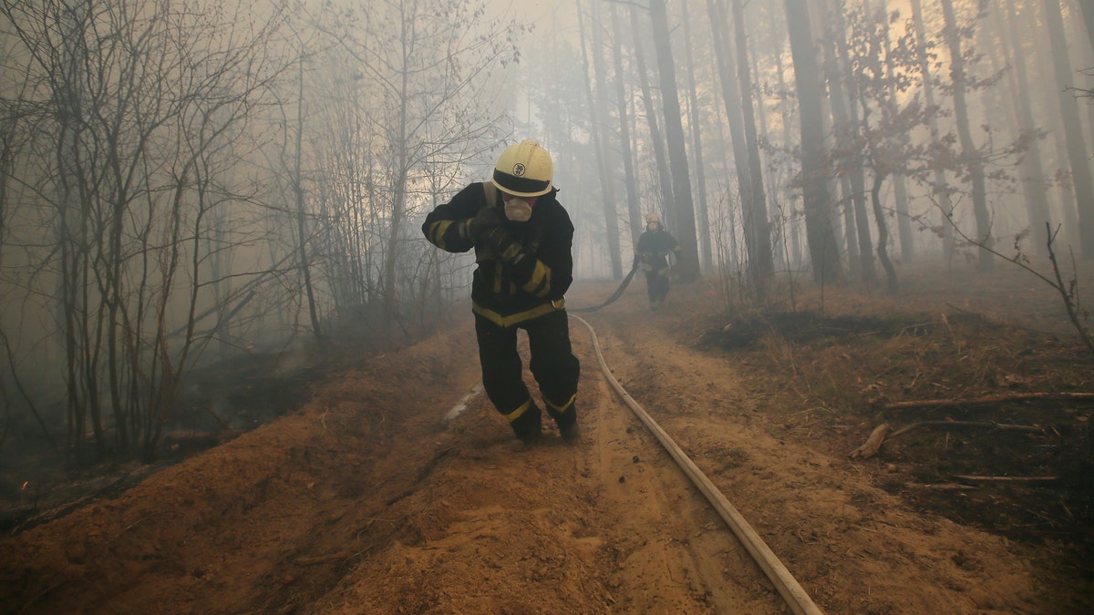 Firefighters extinguish a fire during a forest fire in Ragovka, Ukraine. Fire from the radioactive Chernobyl zone was approaching the village of Ragovka, April 10, 2020.