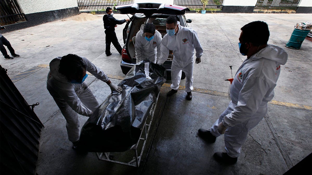 Workers move the body of a COVID-19 victim to the crematorium inside the Panteón San Nicolás Tolentino cemetery in the Iztapalapa neighborhood of Mexico City, Tuesday, June 2, 2020. Funeral parlors and crematoriums in Iztapalapa, a borough of 2 million people, say they have seen their work multiplied with the surging number of dead of COVID-19 in the capital's hardest-hit corner by the new coronavirus. (AP Photo/Marco Ugarte)