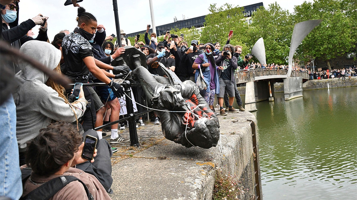 Protesters throwing the statue of slave trader Edward Colston into the Bristol harbor. (Ben Birchall/PA via AP)