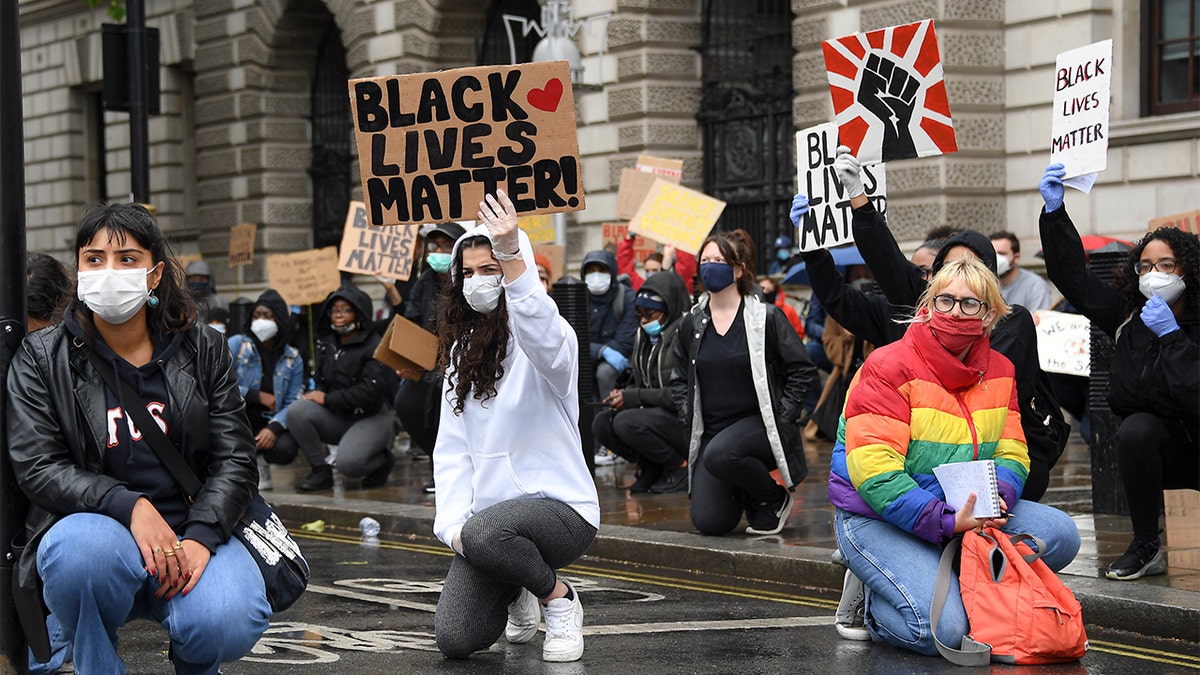 Demonstrators hold placards during a Black Lives Matter rally in Parliament Square in London, Saturday, June 6, 2020, as people protest against the killing of George Floyd by police officers in Minneapolis, USA. Floyd, a black man, died after he was restrained by Minneapolis police while in custody on May 25 in Minnesota. (AP Photo/Alberto Pezzali)