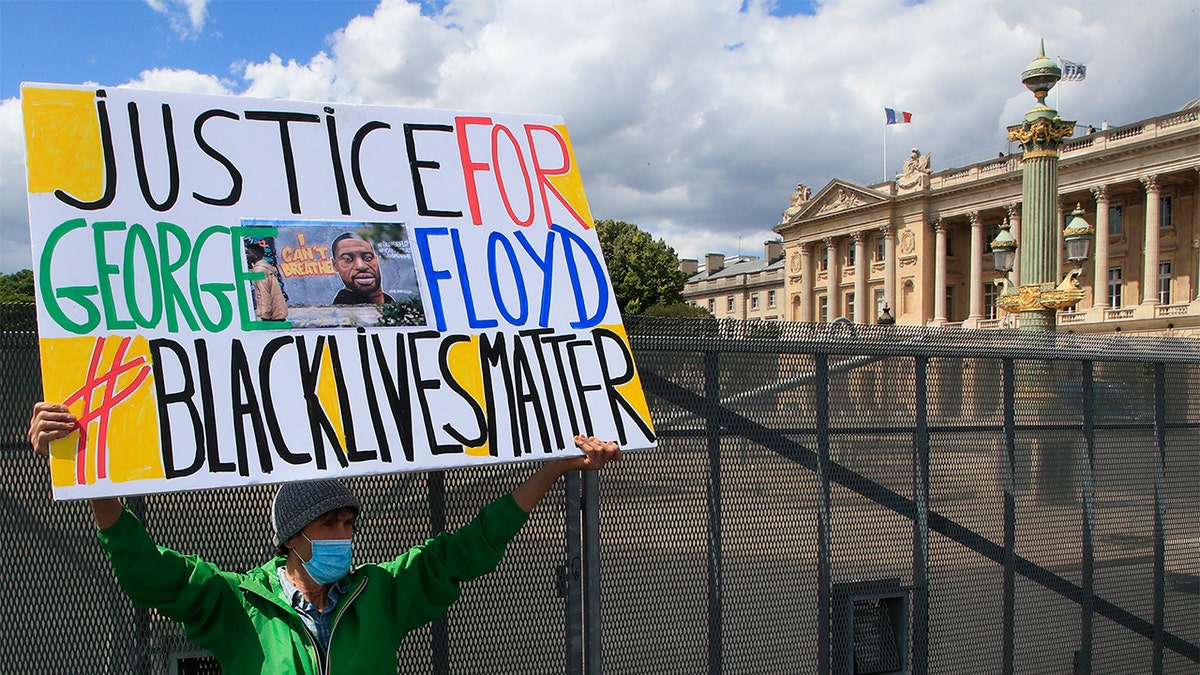 A man holds a placard during a demonstration in Paris, France, Saturday, June 6, 2020, to protest against the recent killing of George Floyd, a black man who died in police custody in Minneapolis, U.S.A., after being restrained by police officers on May 25, 2020. (AP Photo/Michel Euler)