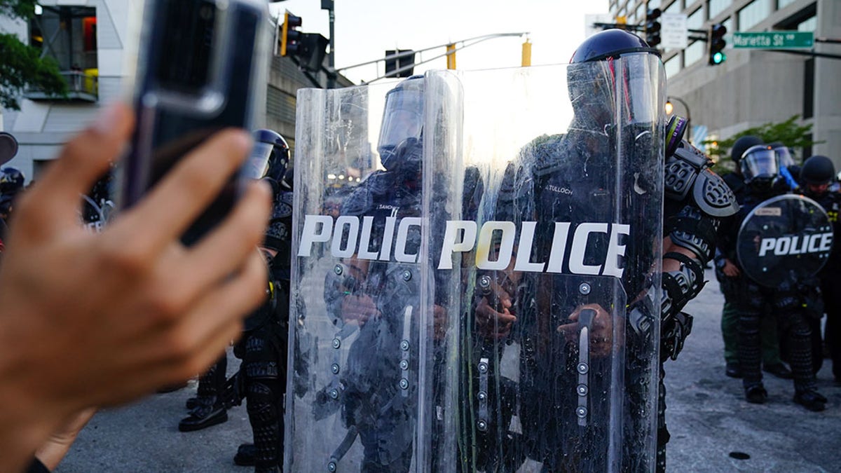 A man records video of a police line during a protest in response to the police killing of George Floyd on May 30, 2020 in Atlanta, Georgia. (Photo by Elijah Nouvelage/Getty Images)