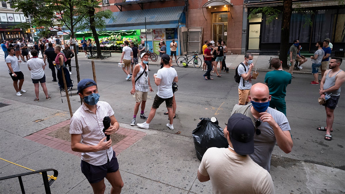 People gather on a street in the Hell's Kitchen neighborhood of New York, Friday, May 29, 2020, during the coronavirus pandemic. The street has been blocked off from traffic to allow residents to gather in open spaces with some social distancing. (AP Photo/Mark Lennihan)