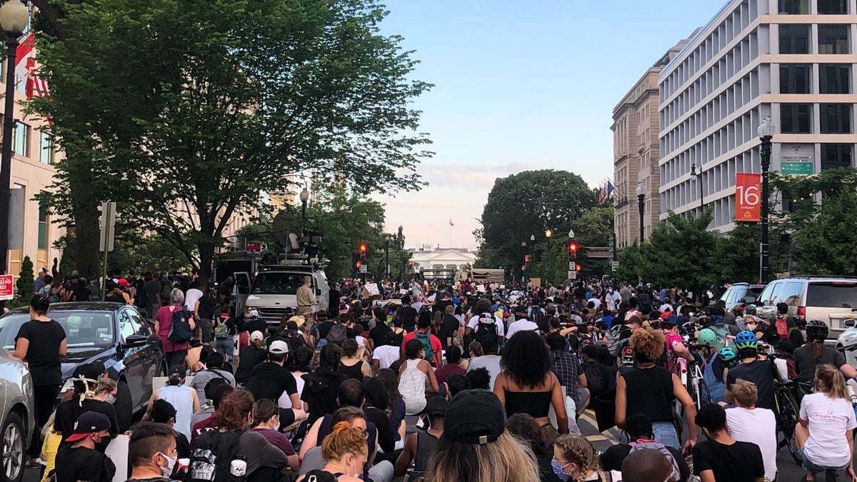 Protesters kneel in front of the White House.