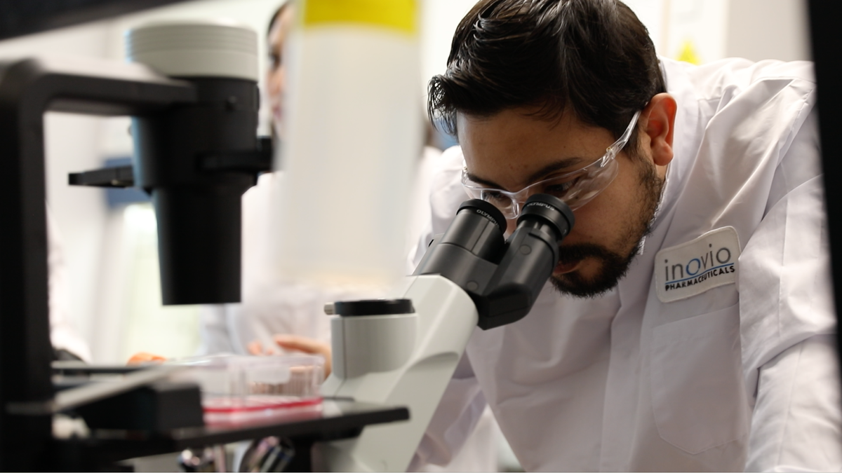 An INOVIO scientist peers into a microscope at the laboratory. (Photo courtesy of INOVIO Pharmaceuticals)