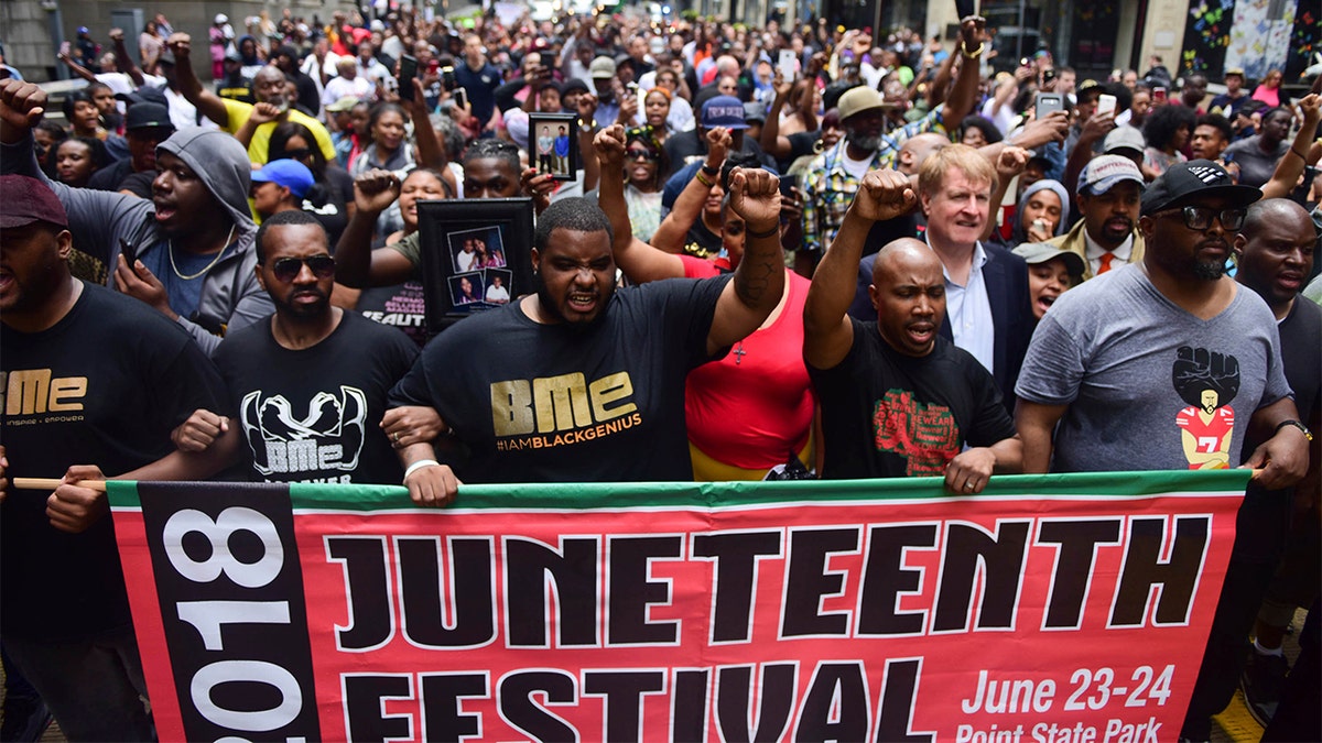 Juneteenth Festival attendees hold sign