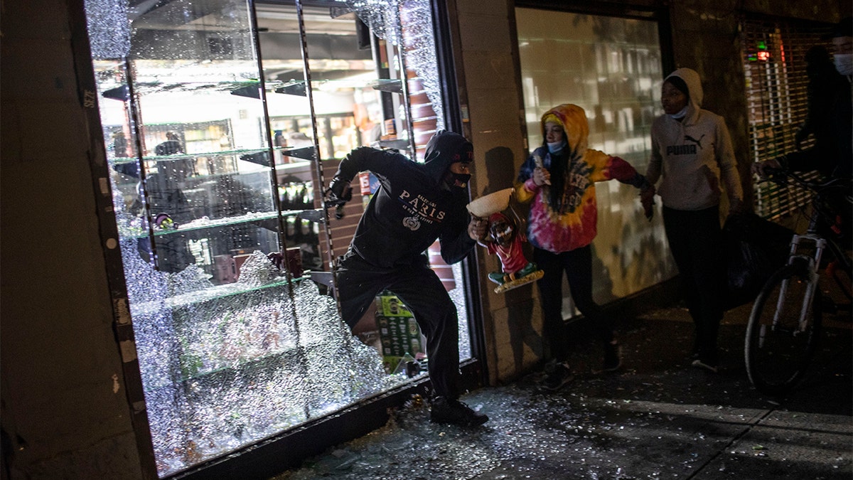 People run out of a smoke shop with smoking instruments after breaking in as police arrive on Monday, June 1, 2020, in New York City.?