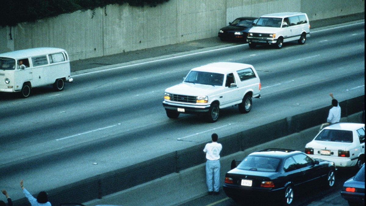 Motorists wave as police cars pursue the Ford Bronco driven by Al Cowlings, carrying fugitive murder suspect O.J. Simpson, on a 90-minute slow-speed car chase June 17, 1994, on the 405 freeway in Los Angeles, California. (Photo by Jean-Marc Giboux/Liaison)