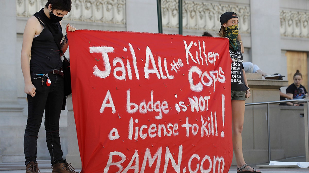 People hold up a sign in Oakland, Calif., Thursday, June 4, 2020, at a protest over the death of George Floyd, who died May 25 after being restrained by police in Minneapolis. (AP Photo/Ben Margot)