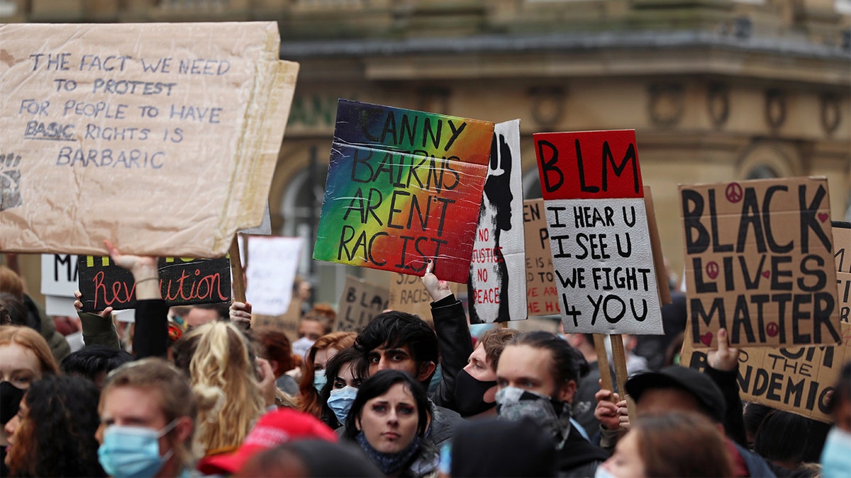 Demonstrators hold signs as they attend a Black Lives Matter protest following the death of George Floyd in Minneapolis police custody, in Newcastle, Britain, June 13, 2020. 