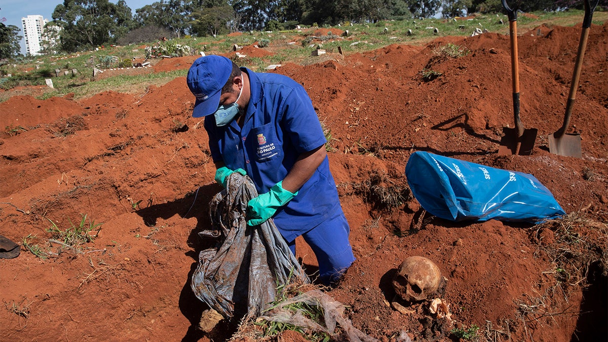 A cemetery worker exhumes the body of a person buried three years ago at the Vila Formosa cemetery, which does not charge families for the gravesites, in Sao Paulo, Brazil, Friday, June 12, 2020. Three years after burials, remains are routinely exhumated and stored in plastic bags to make room for more burials, which have increased amid the new coronavirus. (AP Photo/Andre Penner)