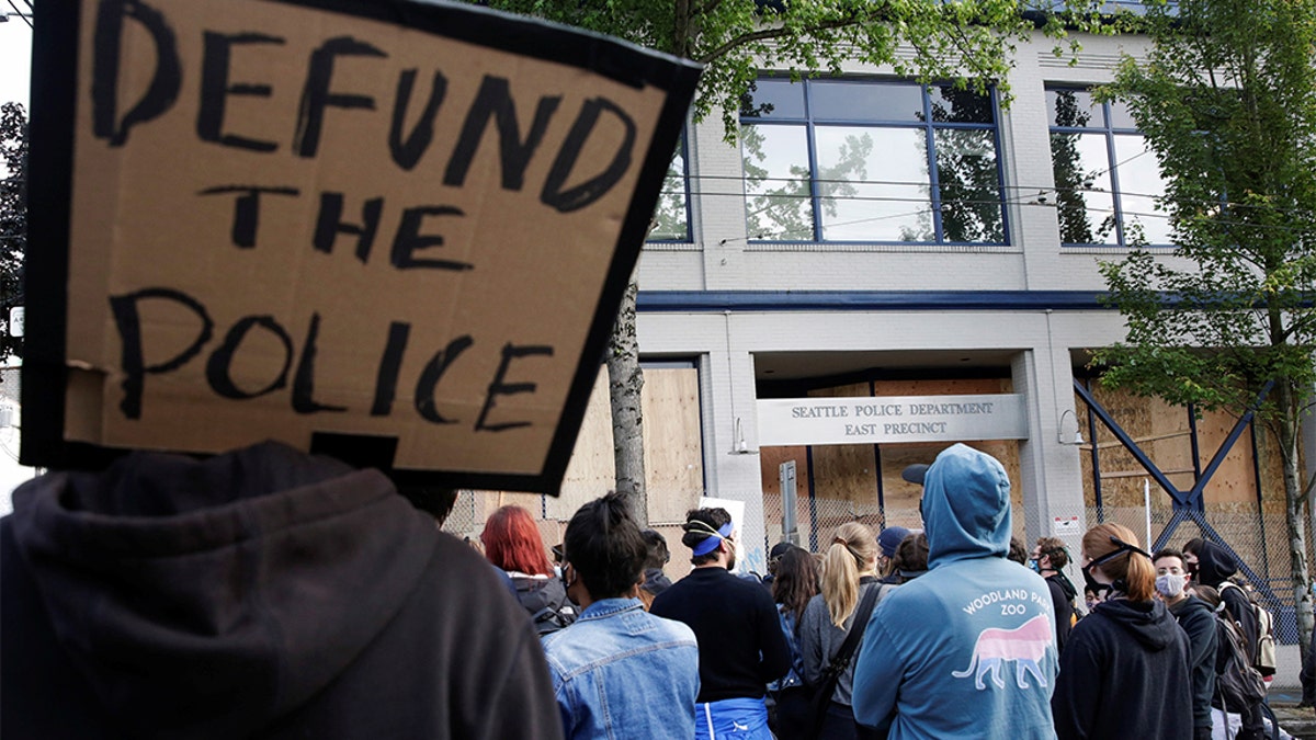 A protester holds a sign that reads "defund the police" after Seattle Police vacated the department's East Precinct and people continue to rally against racial inequality and the death in Minneapolis police custody of George Floyd, in Seattle, Washington, U.S. June 8, 2020. (REUTERS/Jason Redmond)