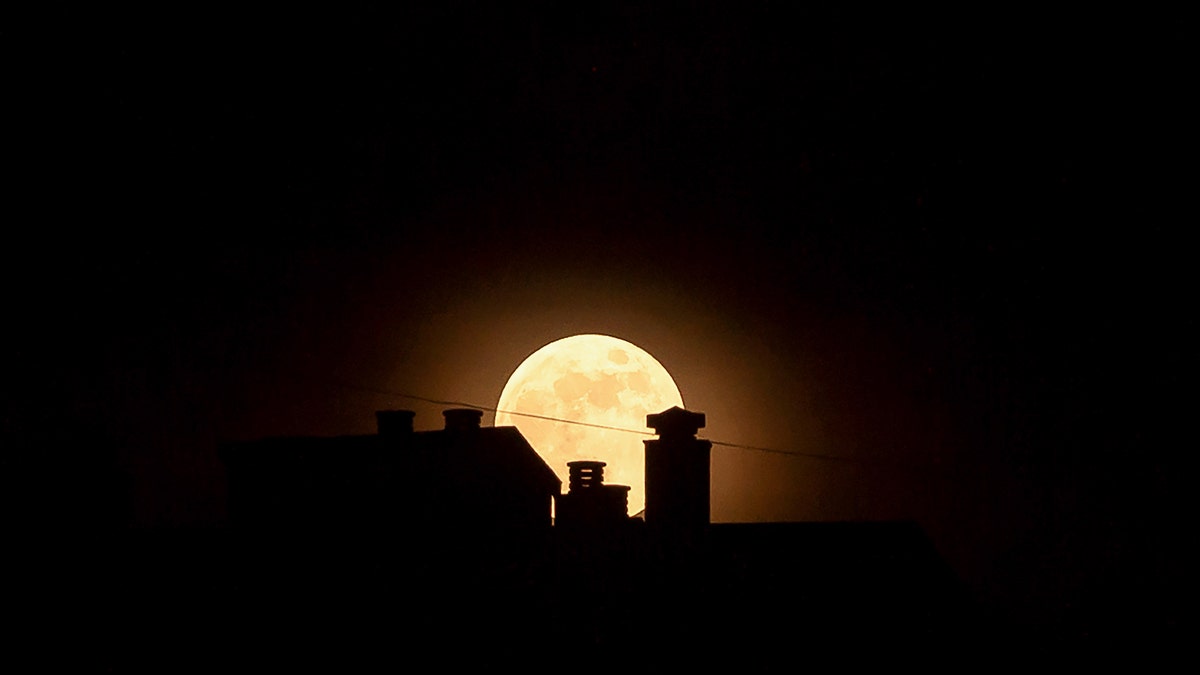 The strawberry full moon, as part of a penumbral lunar eclipse, is seen silhouetted in Malaga, Spain, on June 5, 2020