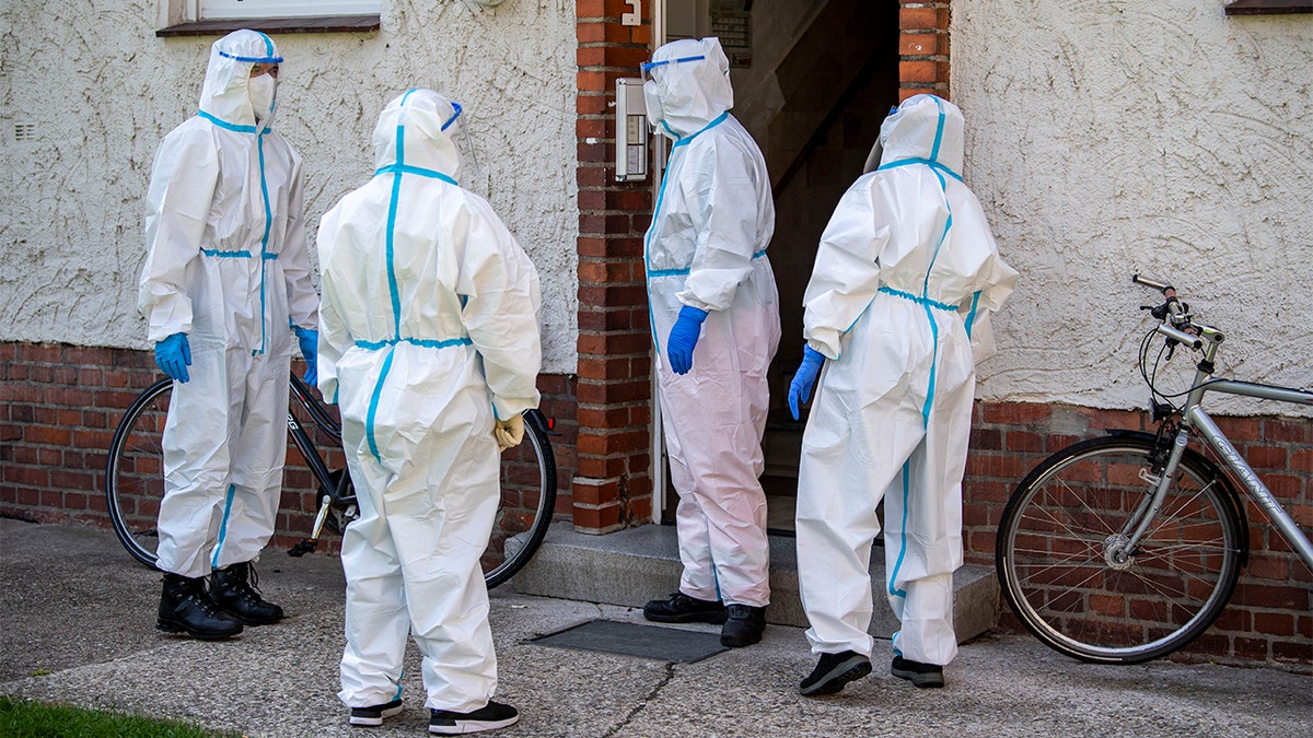 Members of German Red Cross (DRK) stand in front of a house where employees of the Toennies meat factory live in Rheda-Wiedenbrueck, Germany, Monday, June 22, 2020. About 40 mobile test teams are on the road that day to visit employees of the Toennies company at home in their quarantine. Hundreds of new coronavirus cases are linked to the large meatpacking plant, officials ordered the closure of the slaughterhouse, as well as isolation and tests for everyone else who had worked at the Toennies site — putting about 7,000 people under quarantiner. (David Inderlied/dpa via AP)