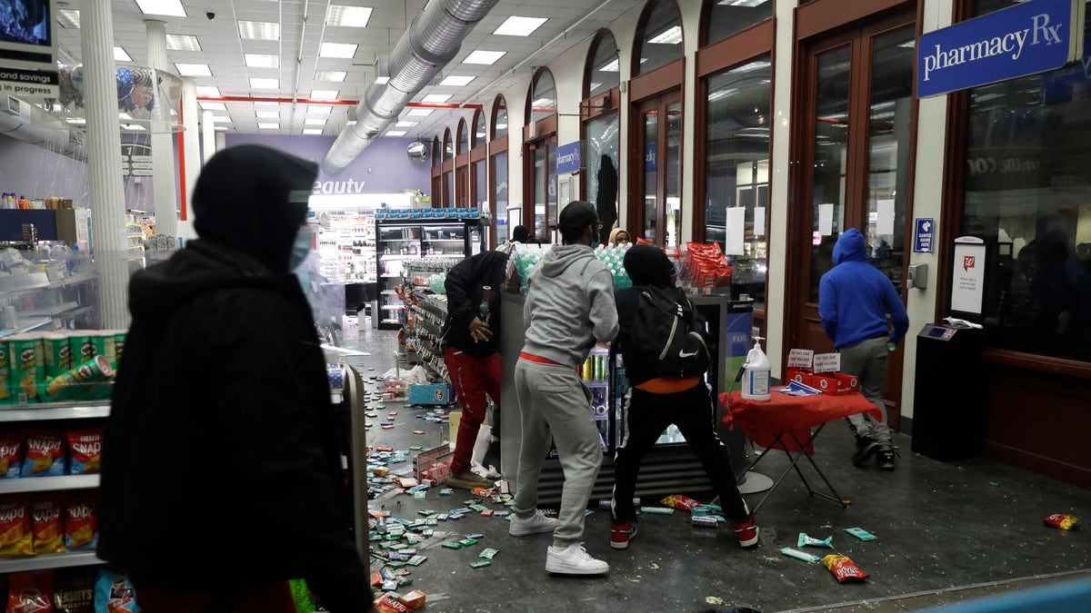 People grab items inside a pharmacy that had its windows broken in New York, Monday, June 1, 2020. (AP Photo/Seth Wenig)
