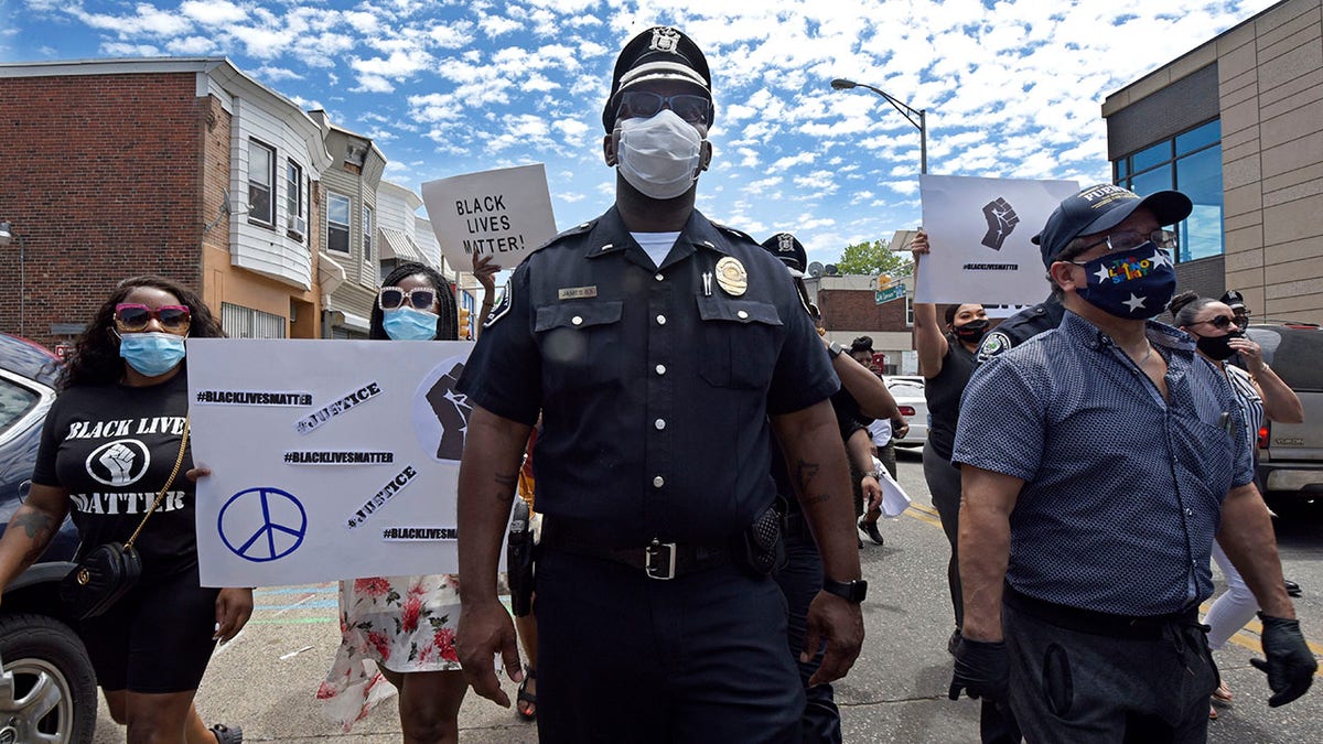 In this Saturday, May 30, 2020, photo, Lt. Zack James of the Camden County Metro Police Department marches along with demonstrators in Camden, N.J., to protest the death of George Floyd in Minneapolis. Police officers in one of New Jersey's largest and most violent cities were praised on social media for marching alongside protesters in rallies held this weekend over Floyd's death. (April Saul via AP)