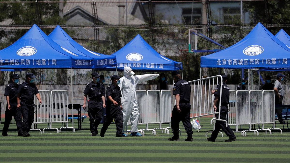 A worker directs security guards as they set up barricades for people who were living surrounding the Xinfadi wholesale market and those have visited to the market to conduct a nucleic acid test at a stadium in Beijing, Sunday, June 14, 2020.