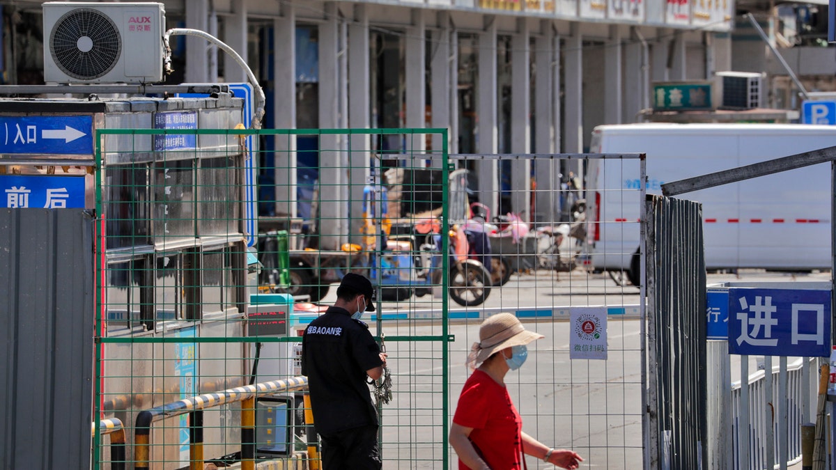 A security guard locks with chain the fence of the seafood wholesale market main entrance which was closed for inspection in Beijing, Sunday, June 14, 2020.