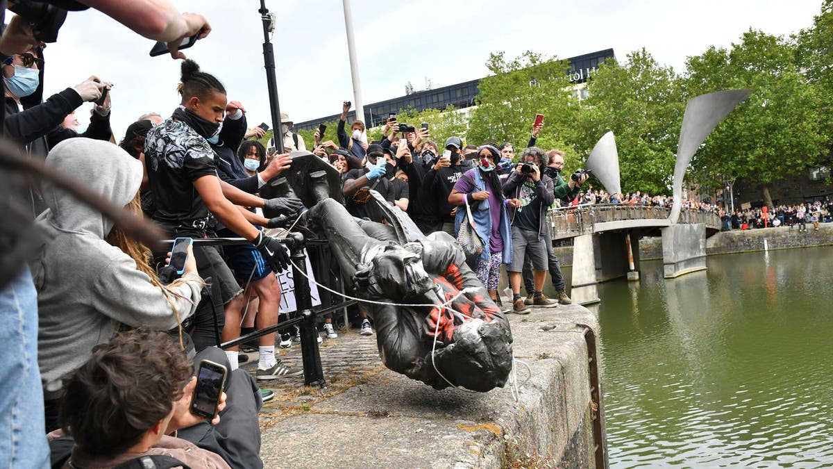 Protesters throw a statue of slave trader Edward Colston into Bristol harbor on Sunday. (AP)