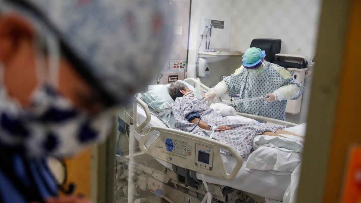 FILE - In this April 20, 2020, file photo, resident physician Leslie Bottrell stands outside a room at an Intensive Care Unit as a nurse suctions the lungs of a COVID-19 patient at St. Joseph's Hospital in Yonkers, N.Y. A U.S. government report says death rates are 12 times higher for coronavirus patients with chronic illnesses than for others who become infected. The Centers for Disease Control and Prevention report Monday, June 15 highlights the dangers posed by these conditions. They include heart disease, diabetes and chronic lung ailments, such as asthma or emphysema. (AP Photo/John Minchillo, File)