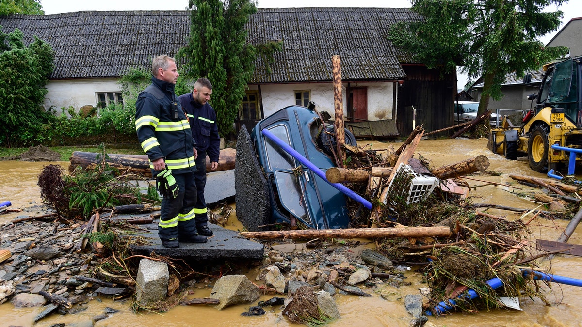Firefighters look on a car trapped in a flooded area in Brevenec, the part of the village of Sumvald in the Olomouc region, Czech Republic, Monday, June 8, 2020.