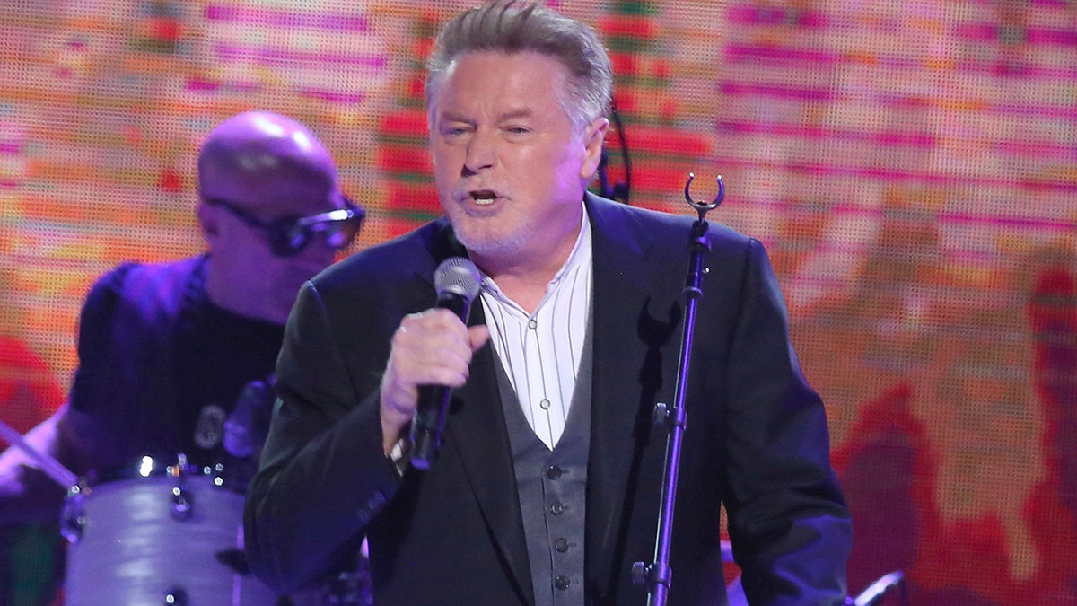 Don Henley performing in a suit with a microphone in 2017