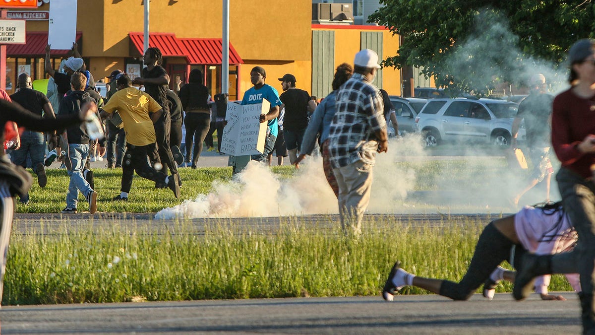 People run from tear gas canisters along U.S. 30 on Sunday, May 31, 2020, in Hobart, Ind., during protests over the death of George Floyd in Minneapolis. (John J. Watkins/The Times via AP)