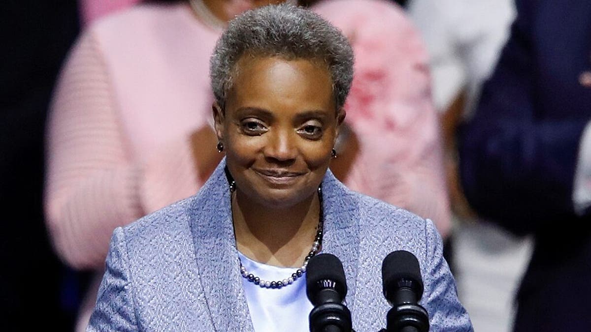 Lori Lightfoot smiling in front of mic