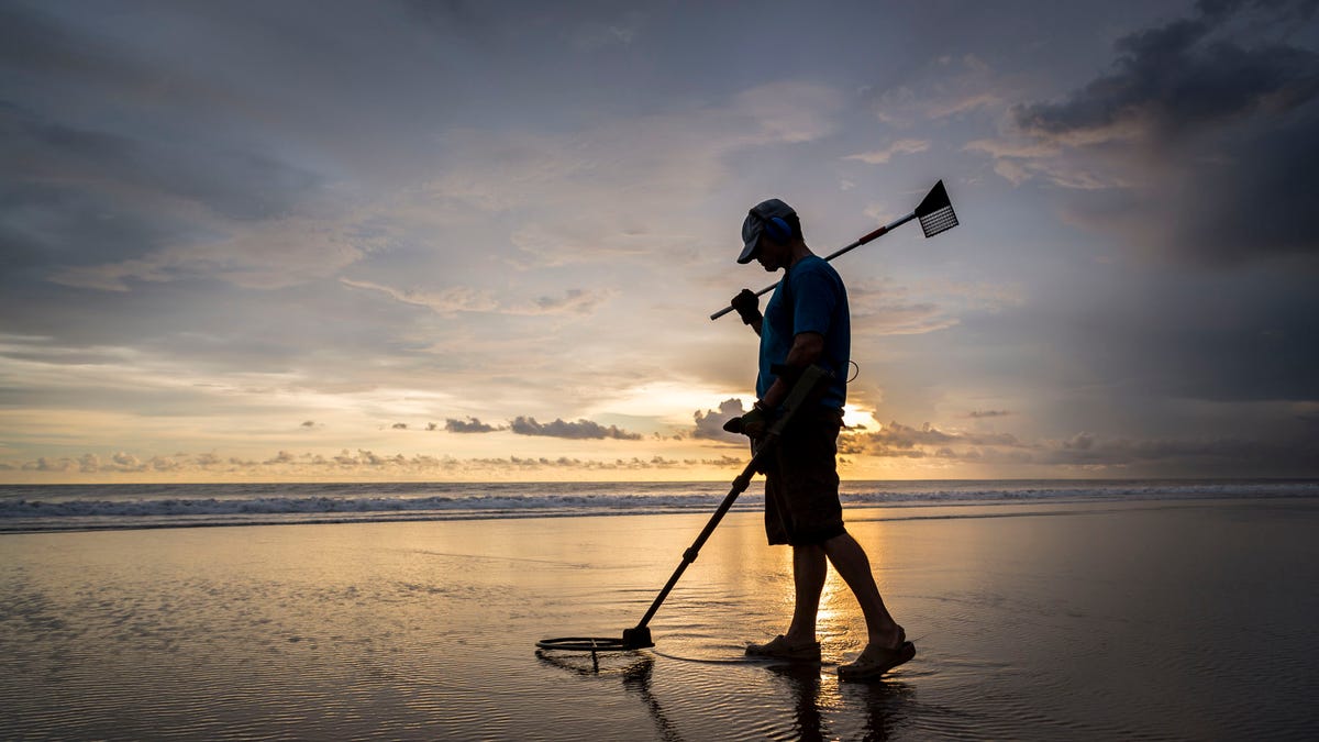 Treasure hunter on the beach with a metal detector