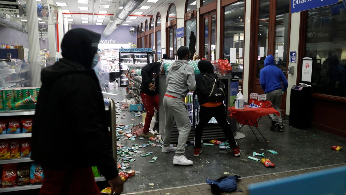 People grab items inside a pharmacy that had its windows broken in New York City early Monday. (AP)