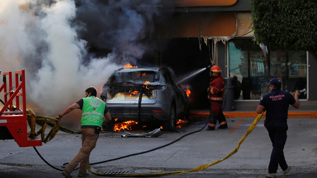 Firefighters work on a burning car outside a store after an operation by security forces against organized crime in Celaya, in Guanajuato state, Mexico June 20, 2020.