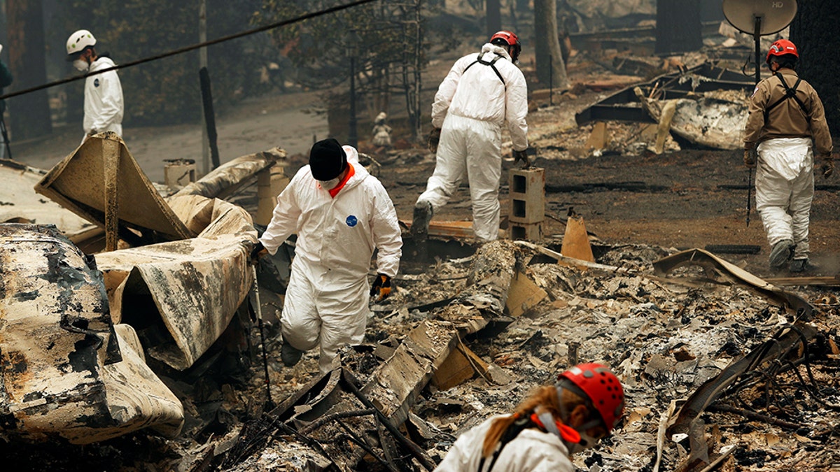 FILE - In this Nov. 13, 2018, file photo, search and rescue workers search for human remains at a trailer park burned out from the Camp Fire in Paradise, Calif. Pacific Gas &amp; Electric officials are to be expected to appear in court Tuesday, June 16, 2020, to plead guilty for the deadly wildfire that nearly wiped out the Northern California town of Paradise in 2018. (AP Photo/John Locher, File)