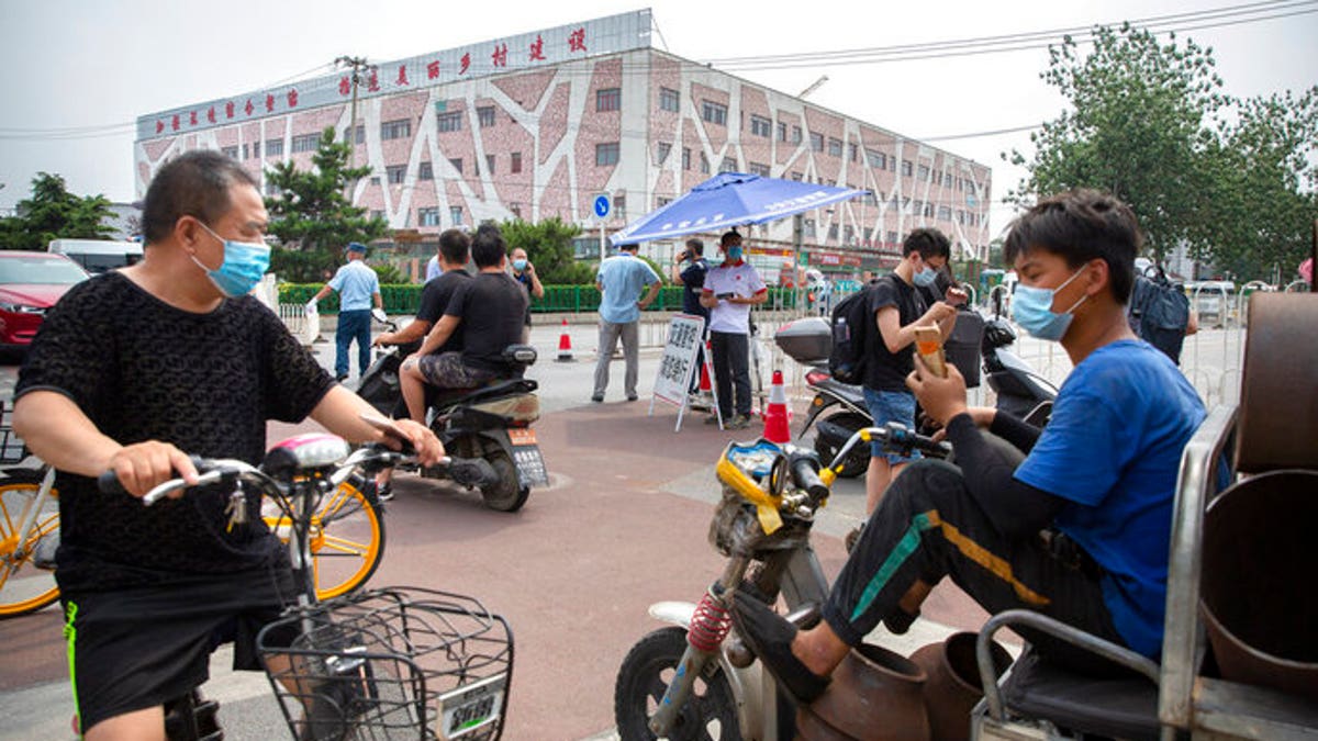 People wearing face masks to protect against the new coronavirus stop at a checkpoint outside the Xinfadi wholesale food market district in Beijing, Saturday, June 13, 2020. Beijing closed the city's largest wholesale food market Saturday after the discovery of seven cases of the new coronavirus in the previous two days.