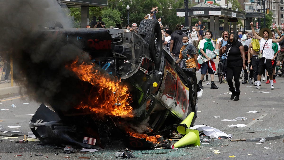 In this May 30, photo, protesters demonstrate as a Salt Lake City police vehicle burns, in Salt Lake City. Police have so far charged eight people in the incident. (AP Photo/Rick Bowmer)