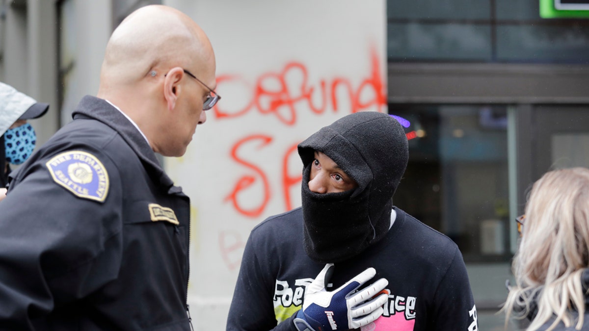 Demonstrator Keith Brown, right, talks with Seattle Fire Dept. Assistant Chief Willie Barrington as they plan to remove makeshift barricades protesters had put up in the streets next to a Seattle police precinct Tuesday, June 9, 2020, in Seattle. (AP Photo/Elaine Thompson)