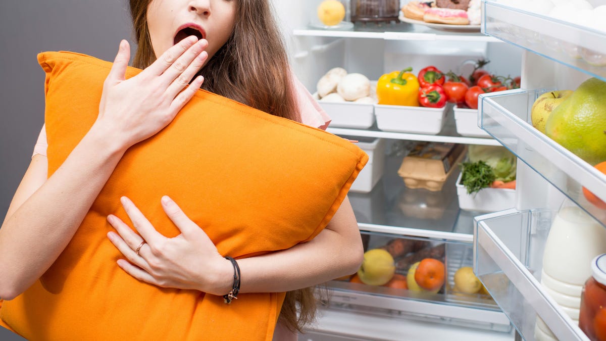 Woman with food near refrigerator