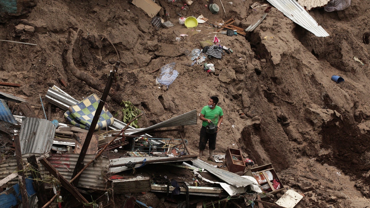 A man seeks to salvage some of his belongings from what used to be his home, destroyed by the waters of the Acelhuate River, in the New Israel Community of San Salvador, El Salvador, Sunday, May 31, 2020.