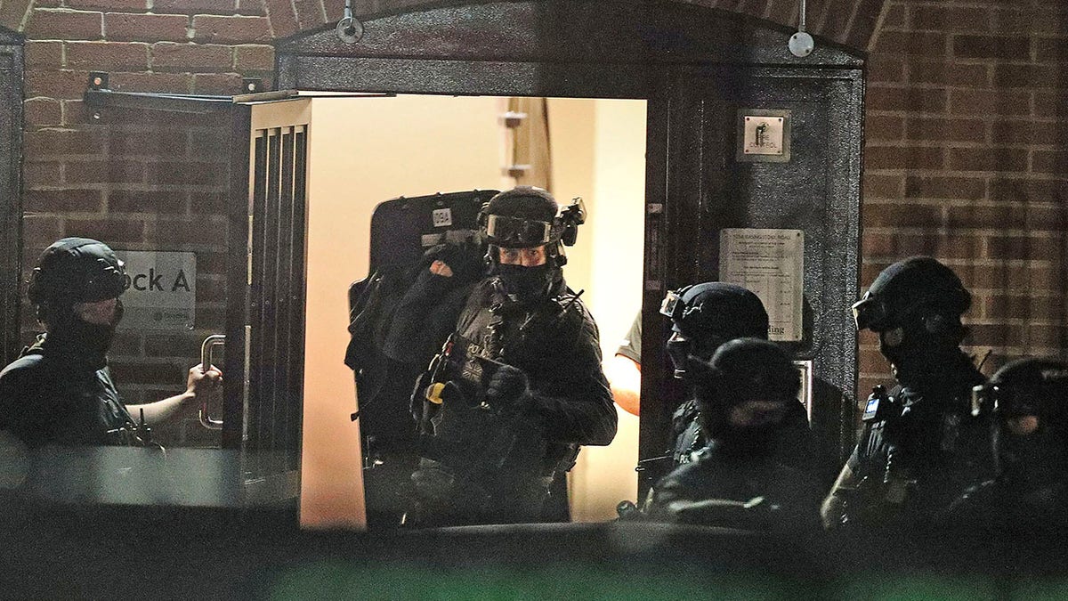 Armed police officers work at a block of flats off Basingstoke Road in Reading after an incident at Forbury Gardens park in Reading, England, Saturday, June 20, 2020. Several people were injured in a stabbing attack on Saturday, and British media said police were treating it as "terrorism-related." (Steve Parsons/PA via AP)