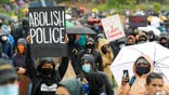 Protester holds "Abolish Police" sign during Seattle protest in 2020