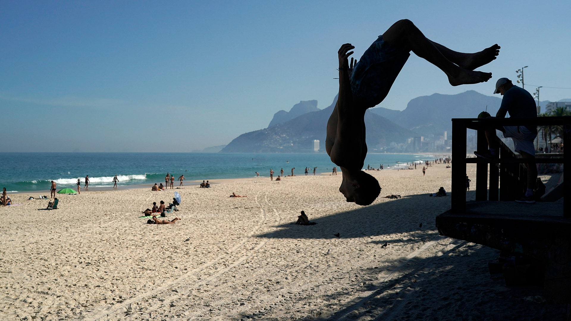 A young man somersaults on Arpoador Beach, amid the new coronavirus pandemic in Rio de Janeiro, Brazil,  June 20, 2020. 