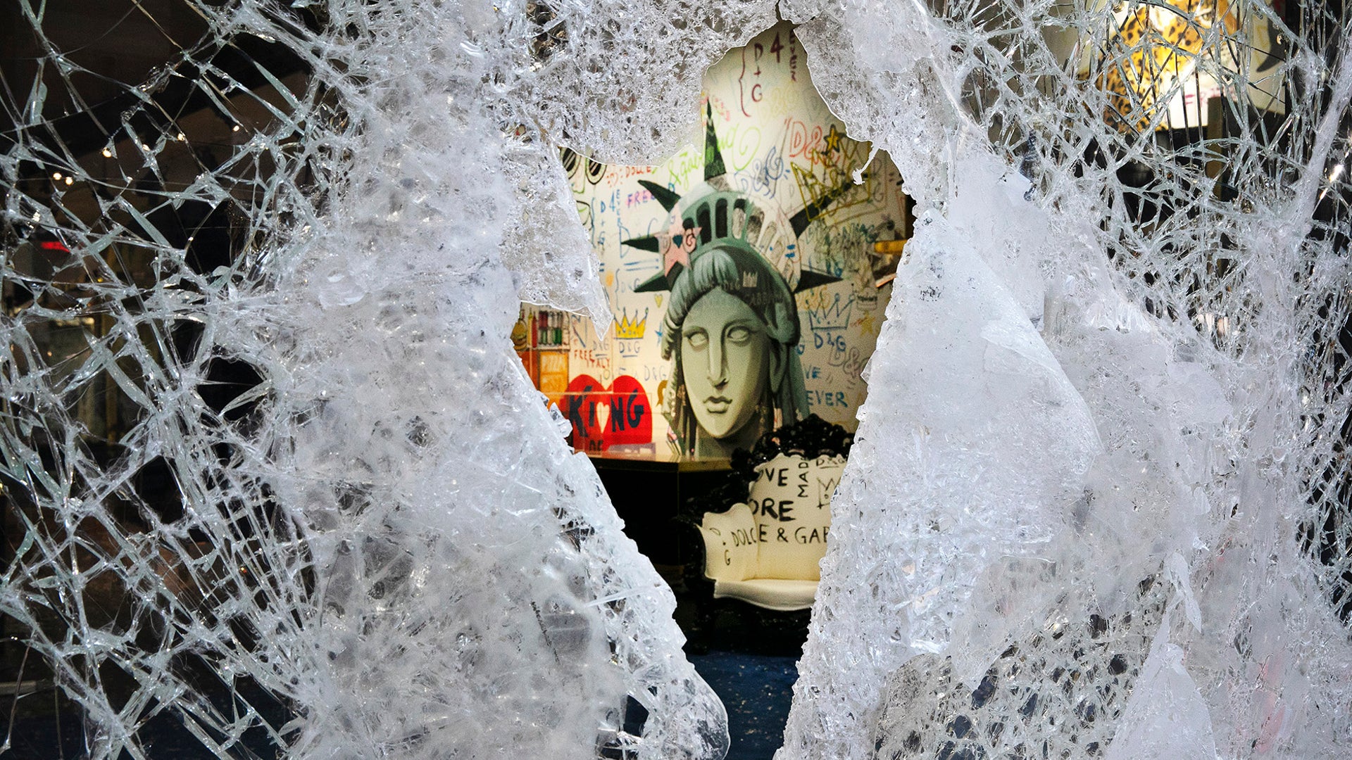 A Statue of Liberty painting is seen through a smashed Dolce and Gabbana store window in the SoHo neighborhood of New York City, June 1, 2020.