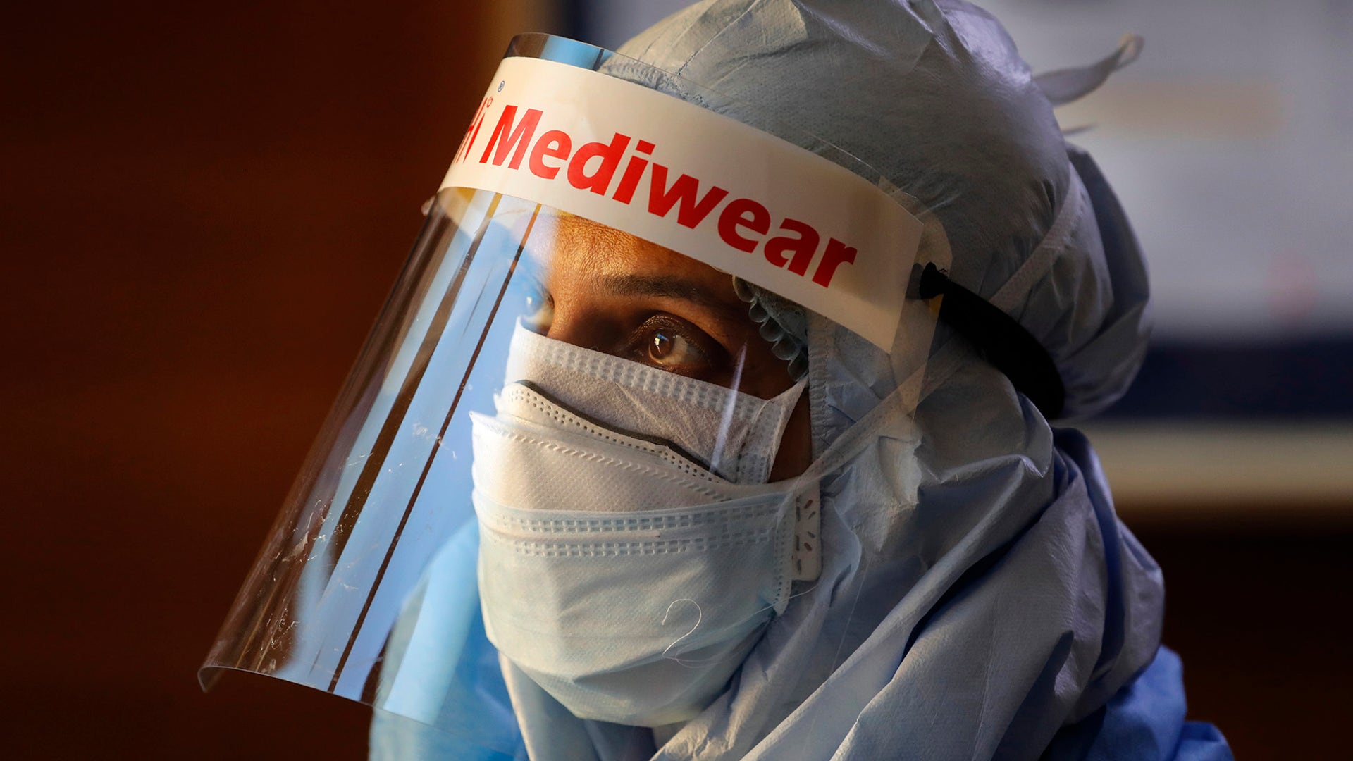 A health worker in a protective suit listens to people standing in a queue for COVID 19 tests at Sir Ganga Ram hospital in New Delhi, India, June 16, 2020.