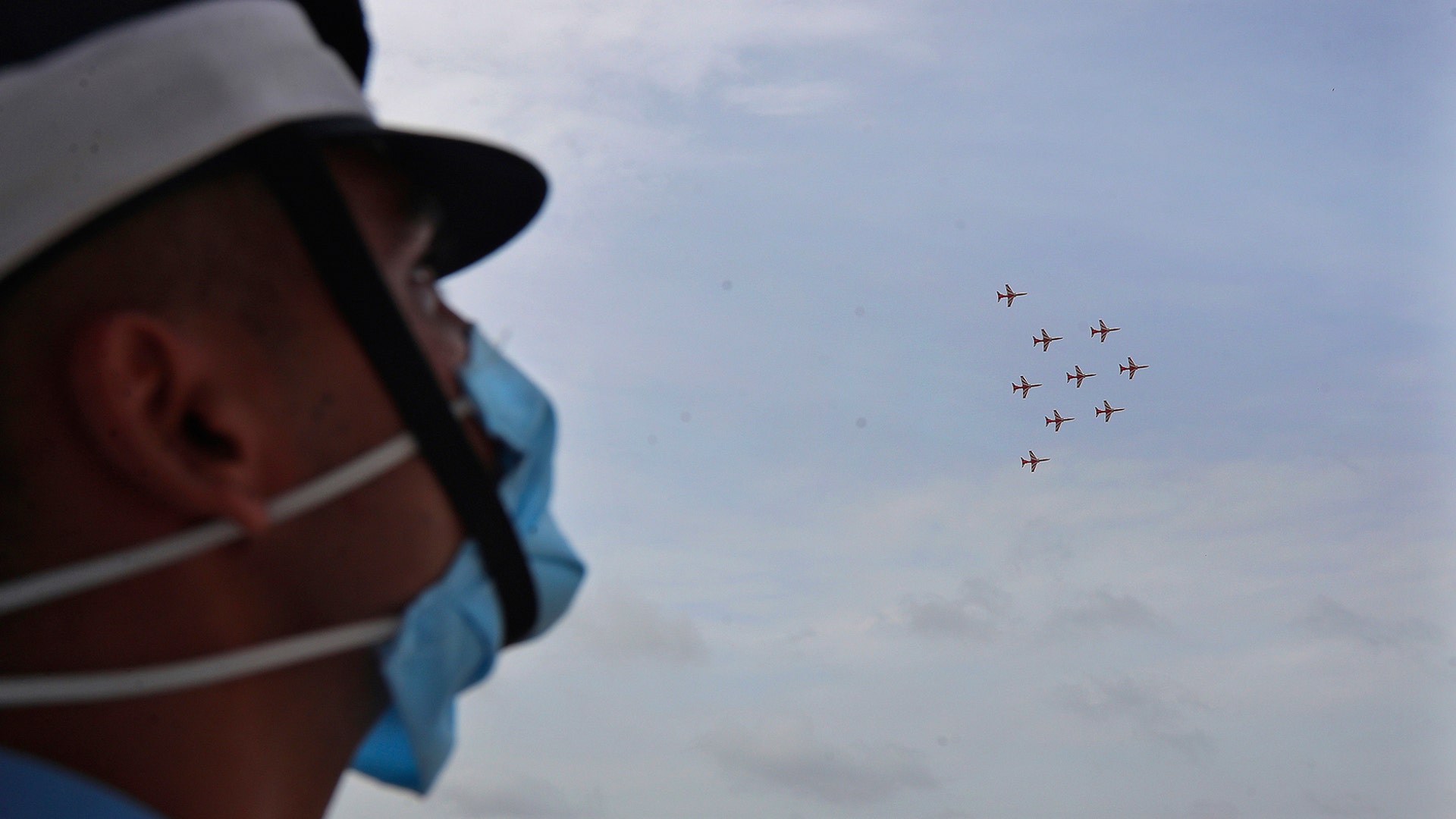 An Indian Air Force cadet watches Surya Kiran aerobatic team perform during a graduation parade at the Air Force Academy in Dundigal, India, June 20, 2020.