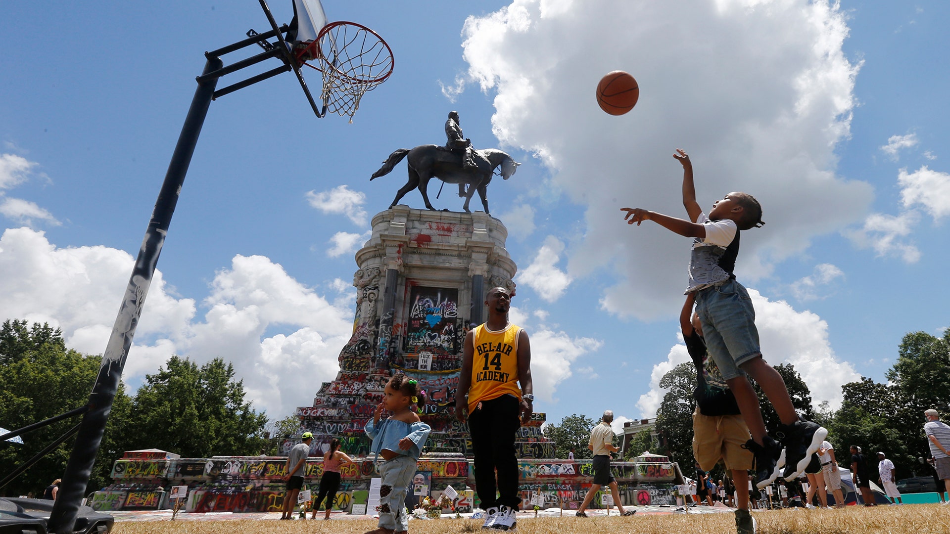 Isaiah Bowen takes a shot as his dad, Garth Bowen, looks on at a basketball hoop in front of the statue of Confederate General Robert E. Lee on Monument Avenue in Richmond, Virginia, June 21, 2020.