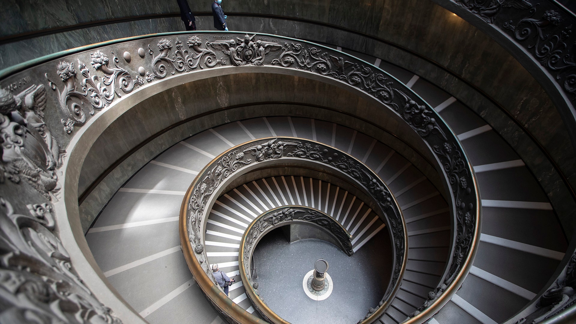 Museum employees, wearing masks to prevent the spread of coronavirus, walk down a staircase designed by Giuseppe Momo in 1932 as the Vatican Museum reopened in Rome, June 1, 2020.